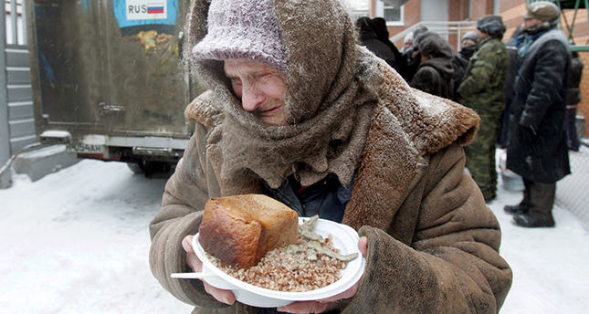 An elderly woman holds a plate of food she received at a distribution point for homeless in Moscow